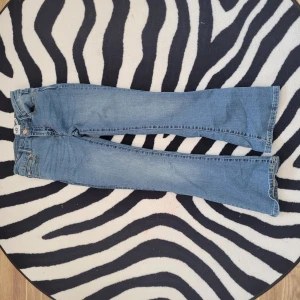 Blå bootcut jeans från 157 Skippy Flare - Snygga ljusblå jeans från 157 med bootcut passform och klassisk femficksdesign. Jeansen har en skön midja och är tillverkade i mjukt denimtyg med kontrastsömmar. Perfekta för dig som gillar retrovibbar och vill ha ett par jeans med lite extra sväng i benen.