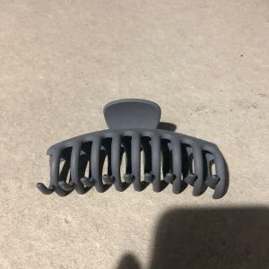 Mörkgrå hårklämma i matt plast - Snygg mörkgrå hårklämma med matt finish och breda, rundade tänder som håller håret på plats. Perfekt för att snabbt fixa en chill uppsättning eller hålla undan håret när du pluggar eller tränar. Enkel och stilren design som passar till allt.