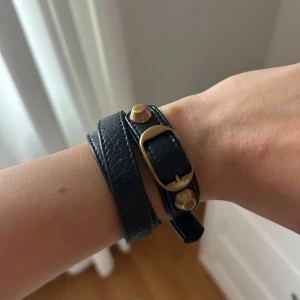 Svart läderarmband med gulddetaljer - Snyggt svart armband i läder från Balenciaga som snurras två varv runt handleden.🥰🥰