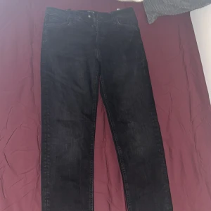 Svarta jeans från Jack & Jones - Säljer ett par svarta jeans från Jack & Jones med klassisk femficksdesign och knappgylf. Jeansen har en rak passform och är tillverkade i slitstarkt denimtyg. Perfekta för dig som gillar en enkel och stilren look.