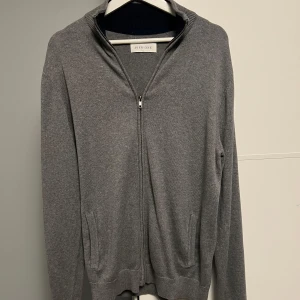 Grå kofta med dragkedja från Pier One - Säljer en stilren grå kofta från Pier One i storlek XL. Koftan har hel dragkedja framtill, ribbad krage och muddar samt två fickor. Materialet är mjuk bomull som känns skönt mot huden. Perfekt för lager-på-lager och chill dagar.