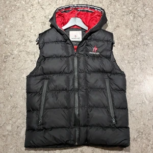 Moncler väst - Moncler väst säljes, Västen är röd inuti och har moncler text inuti som följs jämte dragkedjan, Moncler västen Kan inte garantera äktehet, kan bytas också, skriv vid minsta funderingar osv🤗