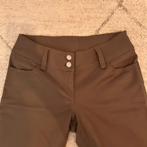 Gröna bootcut-byxor från Weekday - Snygga gröna bootcut-byxor från Weekday i storlek 38. Modellen har medel/låg midja, två framfickor och dubbla silverknappar framtill. Bild 4 visar färgen bäst