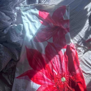 Vit tubklänning med stora röda blommor - Säljer en snygg tubklänning i vit med stora röda blommor som motiv. Endast testad.