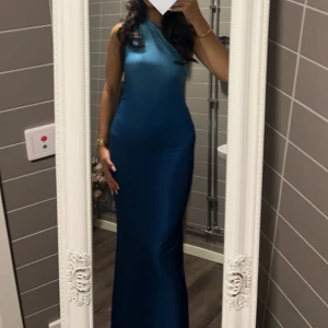 Blå lång klänning med oneshoulder - Säljer en elegant blå långklänning med oneshoulder-design. Klänningen har en tight passform som framhäver figuren, endast använt en gång. Klänningen är M men passar XXS, XS och S