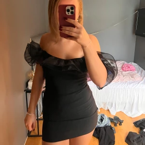 Svart offshoulder kortklänning - Säljer en svart kortklänning med offshoulder och volangdetaljer🥰