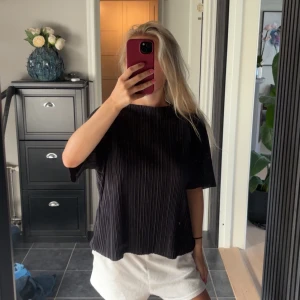 Svart ribbad t-shirt med kort ärm - Säljer en svart t-shirt med ribbad struktur och korta ärmar. Tröjan har en loose passform och är perfekt för dig som gillar en enkel men stilren look. Materialet känns mjukt och luftigt mot huden. Passar dig som vill ha en chill vibe.