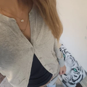 Ljusgrå kofta med knappar - Säljer en stilren ljusgrå kofta med rund hals och knäppning framtill. Koftan har långa ärmar. Är gjord i mjukt material som känns skönt mot huden. Perfekt att slänga över en t-shirt eller linne för en chill look.