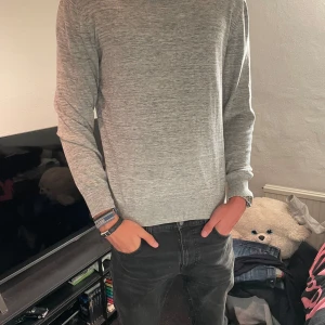 Ljusgrå stickad tröja från J lindeberg - Säljer en stilren ljusgrå J lindeberg tröja, storlek L men sitter som en tajt M, pytte lite liten på mig som är 193cm o 78kg. Inga defekter alls vad jag vet.