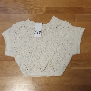 Vit stickad topp från Zara - Säljer en söt vit stickad topp från Zara med korta ärmar och dekorativa stickade detaljer. Helt ny med tag kvar, säljer då jag fick den i present men inte är min stil❤️