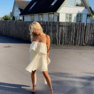 Vit axelbandslös volangklänning från H&M - INTRESSEKOLL på min jättefina klänning!  en superfin vit axelbandslös klänning med volangdetaljer och asymmetrisk design. Klänningen har en luftig känsla och passar perfekt för varma dagar. Materialet är lätt och ger en elegant look. Två första bilderna är lånade❣️