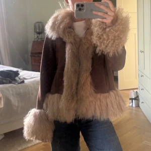 Brun pälsjacka från Charlotte Simone - Säljer en brun pälsjacka från Charlotte Simone med fluffiga detaljer vid krage, ärmslut och nederkant. Jackan har en lyxig och statement look med långärmad passform och mjukt material. 