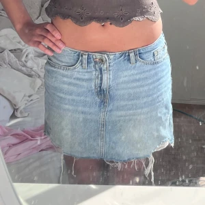 Ljusblå jeanskjol  - Säljer en ljusblå jeanskjol med fransig nederkant och klassiska fickor både fram och bak. Kjolen har en kort passform och stängs med dragkedja och knapp framtill. Perfekt för sommaren. 