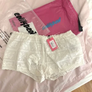 Vita spetsshorts från edikted - Säljer ett par skitsnygga lågmidjade vita shorts i spets från edikted. Snörning i midjan och volangkant nedtill. St M men passar snarare S