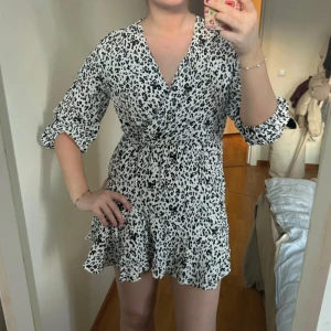 Vit och svart omlottklänning med leopardmönster - Vit miniklänning i leopard-mönster som går i svart och mörkblått. Trekvartsärmar och supergullig volang nedtill. Använd en gång 🐆🖤
