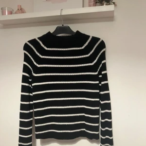 Svart och vit randig stickad tröja från Gina Tricot - Säljer en svart stickad tröja från Gina Tricot med vita horisontella ränder. Tröjan har lång ärm och en något högre rund halsringning. Perfekt för dig som gillar klassiska mönster och mjuka material.