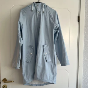 Regnkappa - Ljusblå regnkappa. Tyvärr lite småfläckig lite här och var, i övrigt hel.