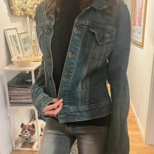Blå jeansjacka  - Säljer en skit snygg blå jeansjacka från H&M. Jackan har en lite mindre passform, långa ärmar och knappar framtill. 
