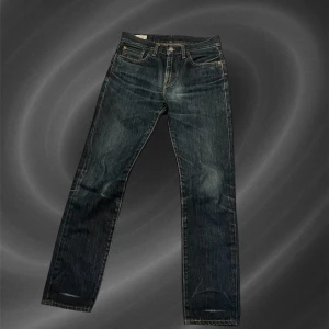 Mörkblåa Levis Jeans - Klassiska Levis jeans i mörkblå tvätt med raka ben och femficksmodell. Byxorna har knappgylf, kontrastsömmar och Levis ikoniska läderpatch bak i midjan. Passar perfekt till en avslappnad stil. (Ser ut som att de är lite gula men det är bara ljustet helt nya och blåa)
