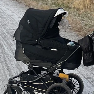  Emmaljunga Vagn 3500kr - Emmaljunga vagn i väldigt fint skick (ingen solblekning osv) har använts väldigt sparsamt. Säljer pga att vi nu istället behöver köpa en tvillingvagn.  2 liggdelar och en sittdel. 1St mörk grå utsida, vit insida 1St som är svart med vita skinn detaljer på utsidan och inuti liggdel är små söta figurer. 1St svart sittdel. Tog ej bild på sittdel då denna är i källaren. Önskas bild på den så är det bara att fråga så ordnar jag det. Kontakta gärna för mer info  3500kr finns i Kista området