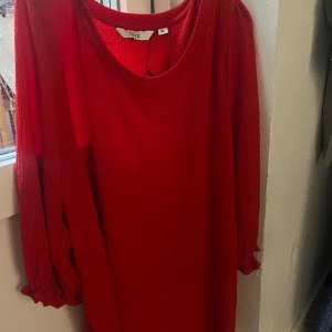 Röd långärmad klänning från Xlnt - Riktigt snygg röd klänning från Xlnt i storlek XL. Klänningen har lång ärm med lätt rynk vid ärmslut och rund halsringning. Materialet är strukturerat och känns mjukt mot huden. Perfekt för dig som vill sticka ut med en färgstark look.