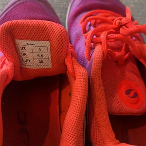 SOC sneakers i lila och neonorange - Färgstarka sneakers från SOC i lila mesh med neonorange detaljer och snörning. Skorna har rund tå, platt sula och är tillverkade i syntetmaterial som andas. Perfekta för dig som vill sticka ut på gymmet eller i vardagen.väldigt lätta