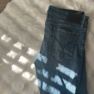 Vintage calvin klein jeans i extremt snygg tvätt - Säljer ett par snygga blå jeans från Calvin Klein med klassisk femficksdesign och diskret logga på bakfickan. Jeansen har en rak passform och normal midja, tillverkade i mjukt denimtyg med lätt slitning. 