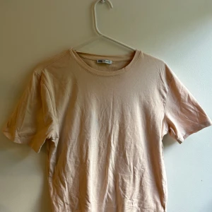 Beige t-shirt från Zara i bomull - Enkel och stilren beige t-shirt från Zara i mjuk bomull. Klassisk rund halsringning och korta ärmar. Perfekt basplagg med normal passform som funkar till allt. Snygg att matcha med jeans eller shorts.