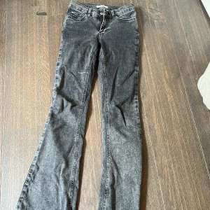 Svarta bootcut jeans från Perfect Jeans - Snygga svarta bootcut jeans från Perfect Jeans med tvättad look och råa, fransiga benslut. Klassisk femficksmodell med dragkedja och knapp. Jeansen har en rak passform upptill och utsvängda ben. 