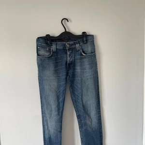 Nudie jeans grim Tim - Säljer ett par mörkblåblå jeans från Nudie Jeans Co, Jeansen är i mycket bra skick och är köpta runt 1200 kr! 