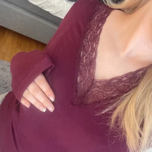 Vinröd långärmad topp med spets - Vinröd långärmad topp från Gina Tricot med v-ringning och snygg spetsdetalj runt halsen. Den är använd 1 gång och är i väldigt bra skick.