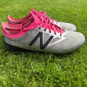 Fotbollsskor från New Balance  - Fotbollsskor i dammodell vilket innebär att de är lite smalare. Använda en säsong. Främst för naturgräs. Innermått på 24,5 cm. 