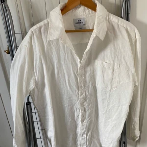 Vit skjorta från New Garments M - Klassisk vit skjorta från New Garments i storlek M. Skjortan har lång ärm, bröstficka och knäppning framtill. Perfekt oversized känsla och tillverkad i ett lätt, vävt material som känns luftigt och fräscht.