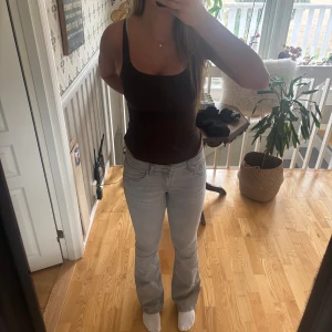 Ljusgrå bootcut jeans - Säljer ett par ljusgrå jeans med bootcut passform och klassisk femficksdesign. Jeansen har normal/låg midja och är tillverkade i mjukt denimtyg som sitter snyggt över höfterna och låren. Perfekta för dig som gillar en stilren och avslappnad look.