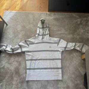 Randig grå hoodie från Acne Studios - ACNE STUDIOS Hoodie med stilrent och unikt mönster. Väldigt bra skick då den använts endast ett fåtal gånger. Storlek M, passar även L då den är lite oversize. Pris går att diskutera, skriv vid fler frågor!