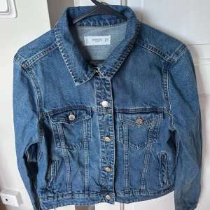  Blå jeansjacka från Mango - Snygg blå jeansjacka med fyra fickor och silverfärgade knappar. Den har raka sömmar och en liten krage. Jättebra skick