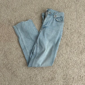 Ljusblå raka jeans från nakd  - Säljer ett par ljusblå jeans från nakd med klassisk femficksdesign och raka ben. Jeansen har hög midja och rå, avklippt fåll nedtill för en avslappnad vibe. Perfekta till sneakers eller boots och funkar året runt.