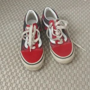 Röda och svarta Vans Old Skool sneakers - Snygga Vans Old Skool sneakers i rött och svart med vita detaljer och klassisk sidorand. Skorna har snörning, platt sula och rund tå. Ovandelen är i mocka och canvas, perfekt för dig som gillar streetstyle och skatekänsla.