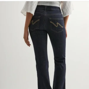 Mörkblå bootcut jeans med broderi - Snygga mörkblå jeans med bootcut-snitt och coolt broderi på bakfickorna. Hög midja och klassisk femficksmodell i jeansmaterial. Perfekta för dig som gillar en tidlös men trendig look.