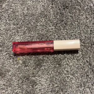 Lumene Luminous Shine Lipgloss - Glansigt läppglans från Lumene i en snygg rosa nyans. Kommer i en rektangulär genomskinlig plasttub med ljusbeige lock. Perfekt för att ge läpparna en fräsch och glansig finish.
