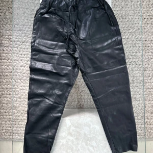 Svarta skinnbyxor från Zara med snörning - Svarta skinnbyxor från Zara med elastisk midja och snörning. Byxorna har raka ben, stora fickor framtill och en lite loose passform. 