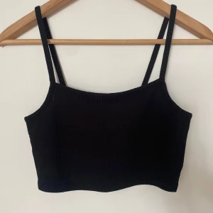 Svart ribbad linnetopp från H&M  - Svart croppad linnetopp från H&M med smala axelband och ribbad, mjuk och stretchig tyg🖤
