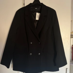 Svart kavaj från Bik Bok - Snygg svart kavaj från Bik Bok i storlek XL. Kavajen har en klassisk design med dubbelknäppning och långa ärmar. Perfekt för en stilren look.