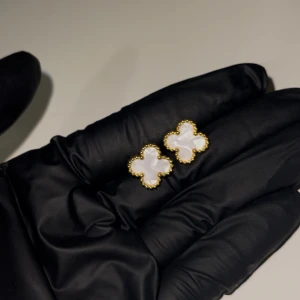 Guld och vita fyrklöverformade örhängen - Eleganta örhängen i form av fyrklöver med vit inläggning och guldfärgad kant. Helt oanvänd, köpt utomlands. Materialet är rostfritt stål med 18K guldplätering. 