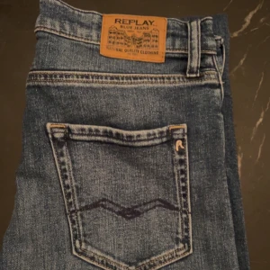 Blå jeans från Replay - Snygga blå jeans från Replay med klassisk femficksdesign och en läderpatch med logotyp baktill. Jeansen har en diskret tvättad look och är perfekta för en avslappnad stil. Priset går att diskutera!