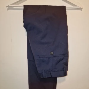 Mörkblå kostymbyxor från J.Lindeberg  - Snygga mörkblå kostymbyxor med en stilren look. De har en klassisk passform och är tillverkade i ett bekvämt material.