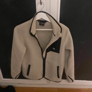 Beige fleece kofta med svarta detaljer från Everest  - Säljer en nu min beigea Everest ull kofta då jag har växt ut den. Koftan har svarta detaljer vid dragkedjan och fickorna, samt en liten logga på bröstet. Perfekt för kyliga dagar! Priset är diskutabelt. 