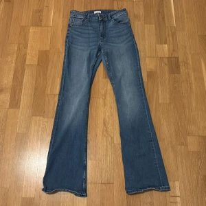 Blå bootcut jeans - Snygga blå bootcut jeans med klassisk femficksdesign. De har en hög midja och är tillverkade i jeansmaterial. Perfekta för en avslappnad stil.