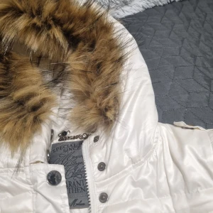 Vit pufferjacka från Mayo Chix - Vintage y2k jacka som jag lagt päls på. jätte fin skick förutom en knapp som har lossnat. Men det märker man inte. Det kan också bli en väst, alltså två i en, därav pris. Titta bild nummer 4. Jackan har dragkedja och knappar framtill samt broderade detaljer på ryggen. 