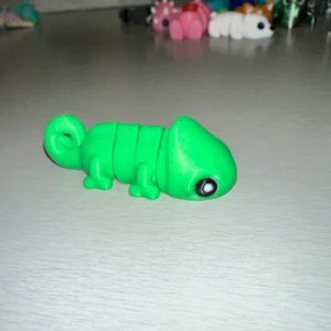 Grön kameleontfigur - En söt liten grön kameleontfigur med stora svarta ögon. Perfekt som dekoration eller leksak. Den har en enkel och stilren design med en slät yta.